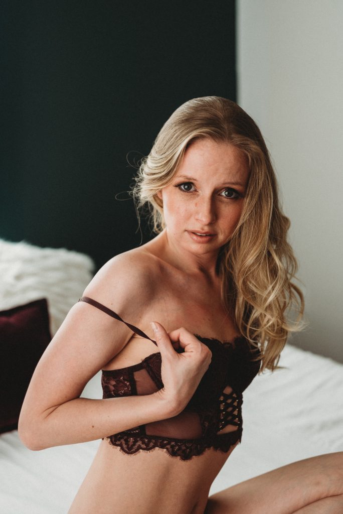 Woman posing in bed wearing lingerie for boudoir photography in Howell, Michigan