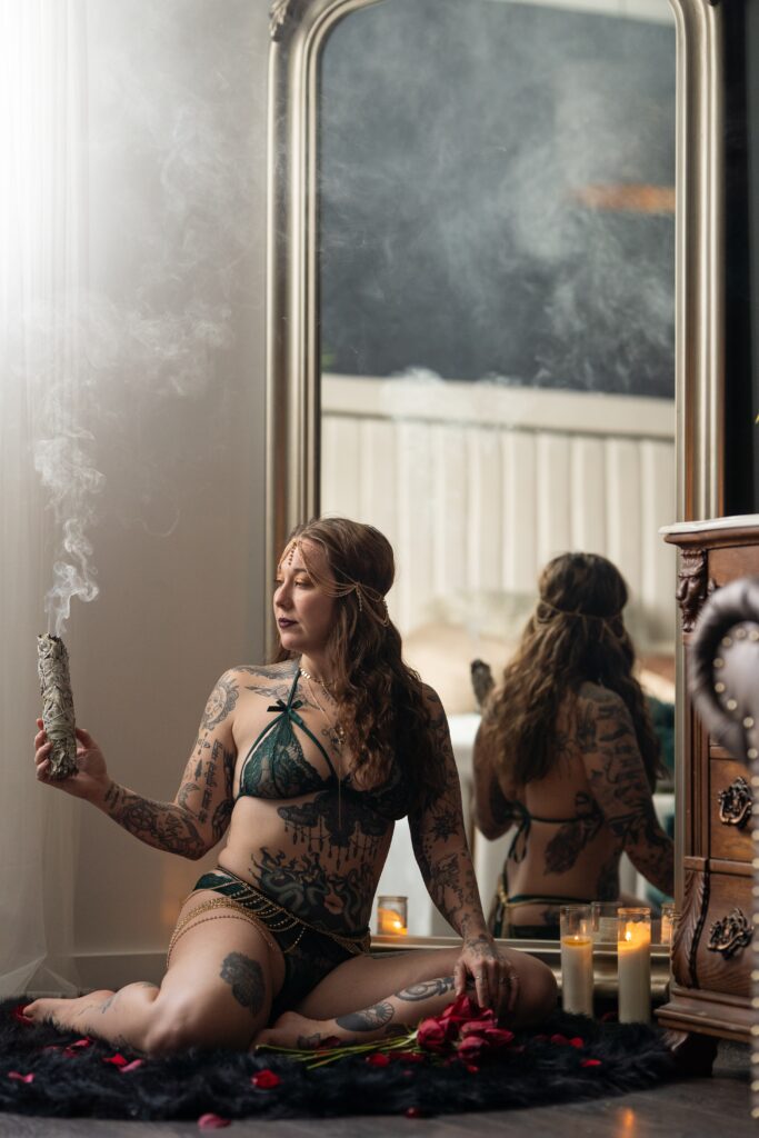 woman buring sage and clearing the energy in the space in a witchy boudoir session