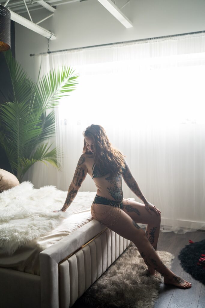 woman sitting on edge of bed during her boudoir session