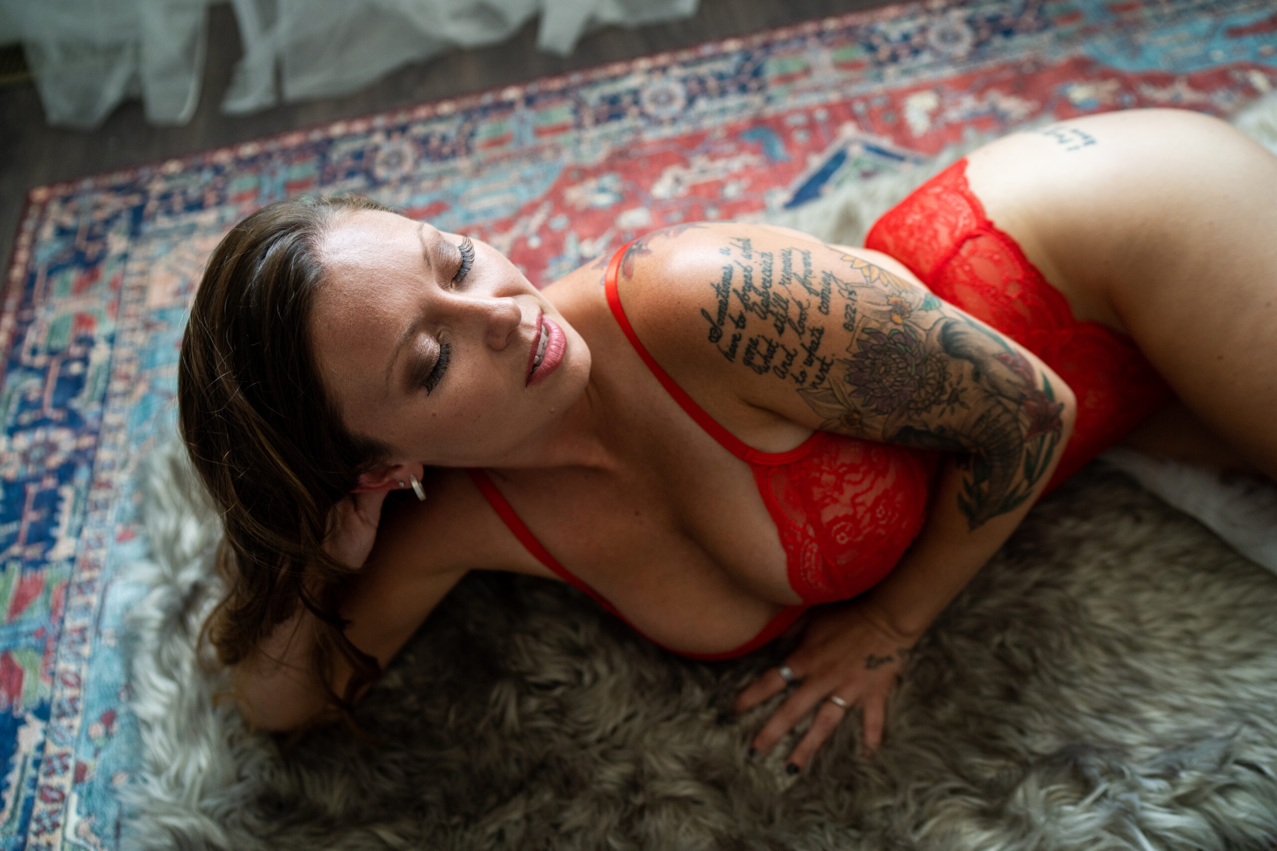 The boudoir portrait Lauren said stunned her: red lace lingerie, head tilted back on a fur rug during her postpartum Detroit boudoir session in Ferndale, Michigan.
